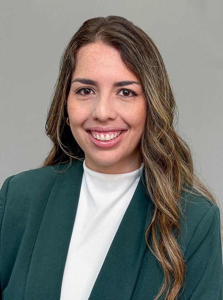 Headshot of attorney Inez Gonzalez in a green jacket and white turtleneck shirt. She is smiling.