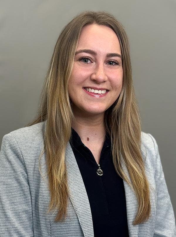 Headshot of Nikol Litvan wearing a gray suit jacket and a black blouse. She is smiling.