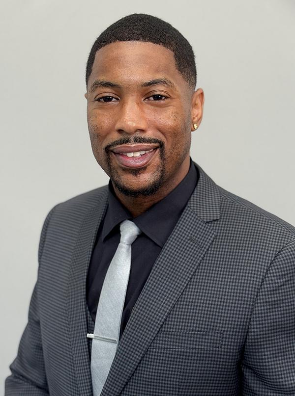 Headshot of Orlandis Jackson in a gray suit and light blue tie. He is smiling.